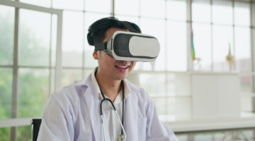Happy young asian male doctor in uniform wearing VR headset and virtual interface. Future medicine and modern technologies gadgets in healthcare concept.