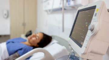 Patient in a hospital bed next to machines.