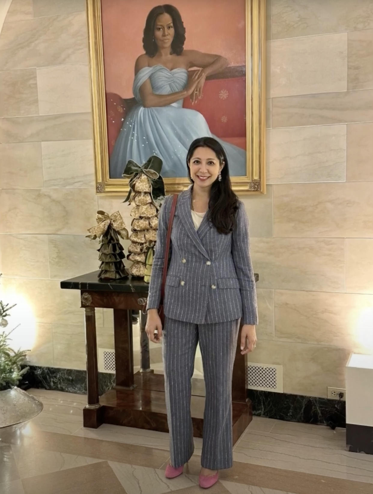 Jannine Versi stands before a portrait painting of Michelle Obama.