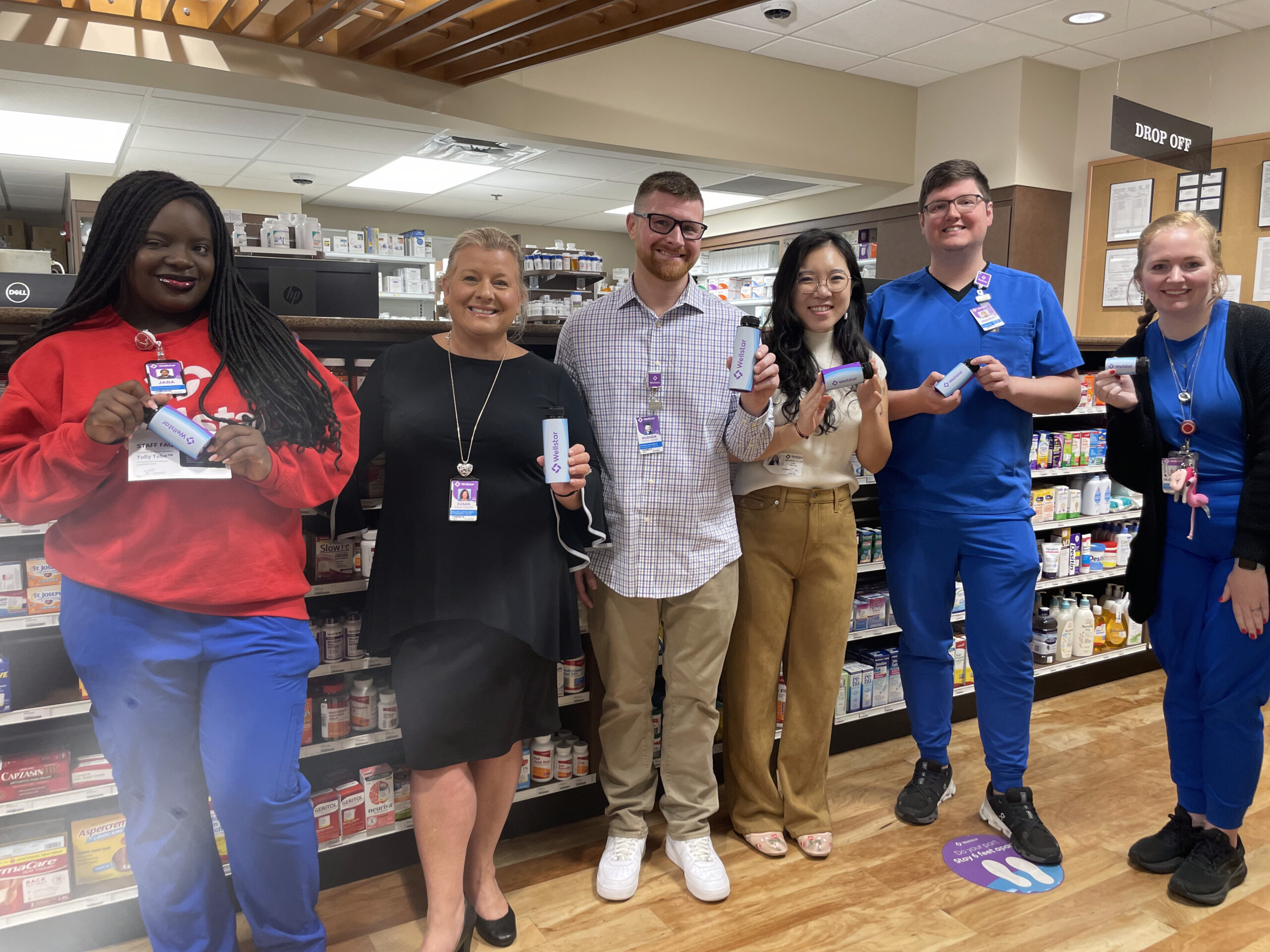 Group of people holding recyclable pill bottles.